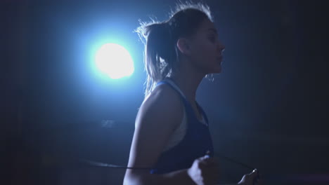 young beautiful woman boxer in training in the hall jumping rope close-up