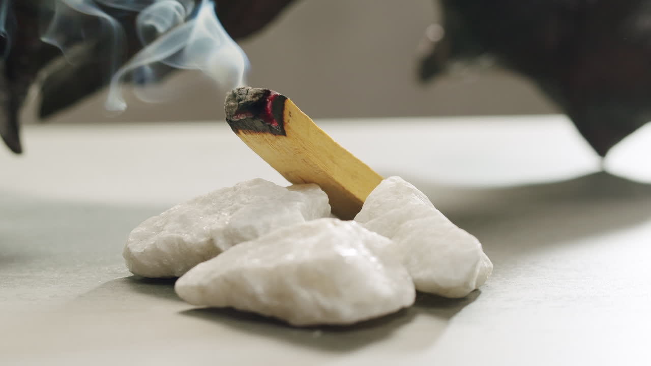 Person holding Palo Santo wood stick in hand, aromatic Palo Santo burning on black background, smoke spreading around, slow motion video clip, high quality 4k close up footage. High quality 4k footage