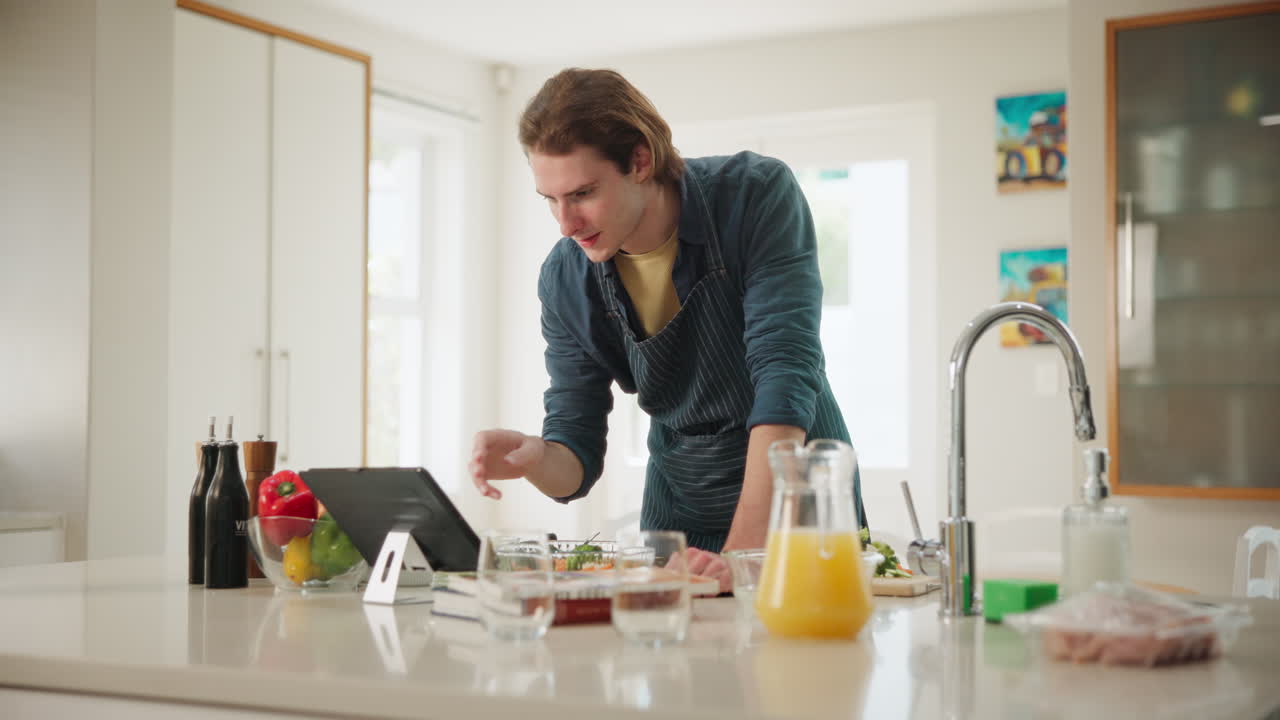 Mand tilbereder mad i køkkenet med en tablet