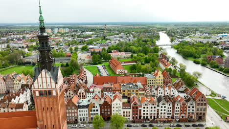 Vista-Panorámica-Del-Casco-Antiguo-De-Elbląg-Con-Una-Arquitectura-Histórica-Con-La-Torre-De-La-Iglesia-En-Primer-Plano-Y-Un-Río-A-Lo-Lejos