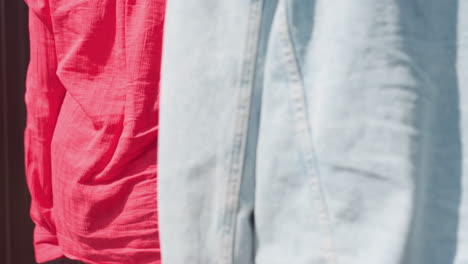 close-up rear view of young women in casual outfits holding black tote and brown shopping bag while walking toward wooden door on bright sunny day