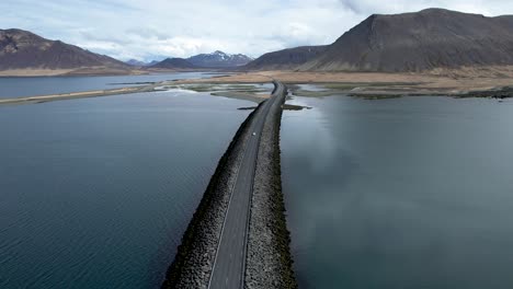 Car-driving-over-long-Sword-shaped-bridge-causeway-through-ocean-bay-in-Iceland