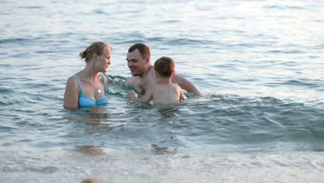 Eltern-Und-Sohn-Spielen-Ball-Im-Meer