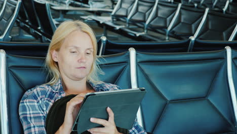 a woman uses a tablet in an airport lounge leisure pending flight