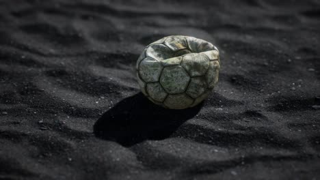 vieja pelota de fútbol en la arena negra