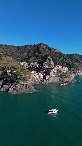 colorful buildings on cliffs overlooking the sea in manarola, italy, with boat