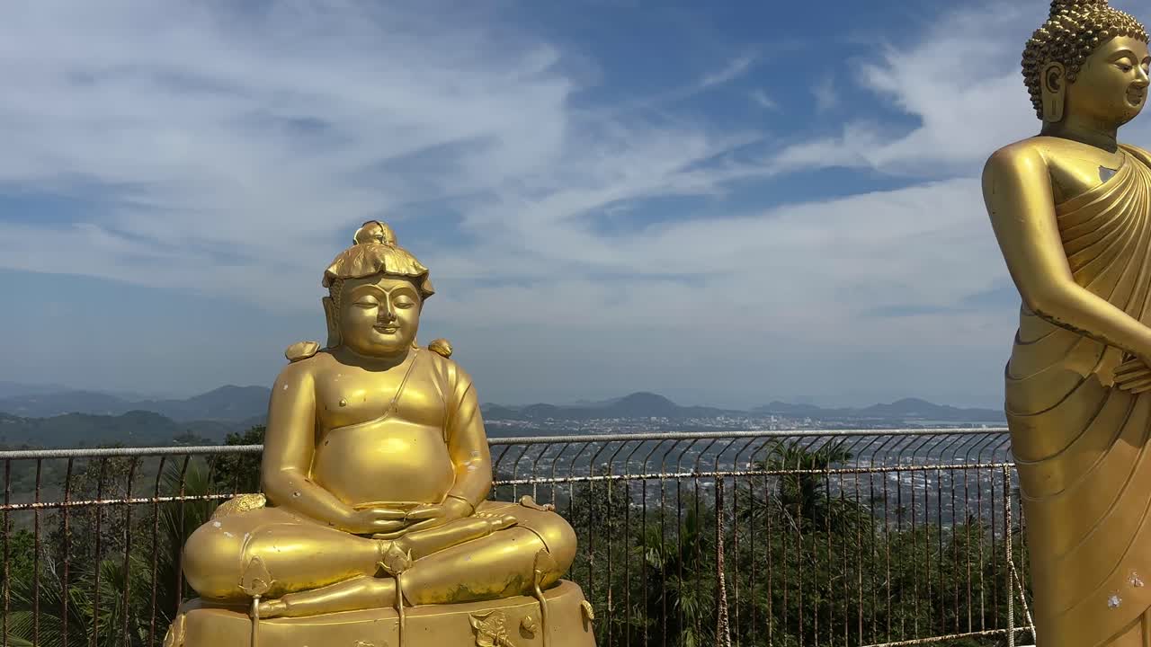 Diverse statue dorate del Buddha, in piedi e sedute, su una terrazza in cima a una collina che si affaccia sulla costa di Karon e Kata. Luogo sacro con cielo all'orizzonte marino e atmosfera spirituale tranquilla