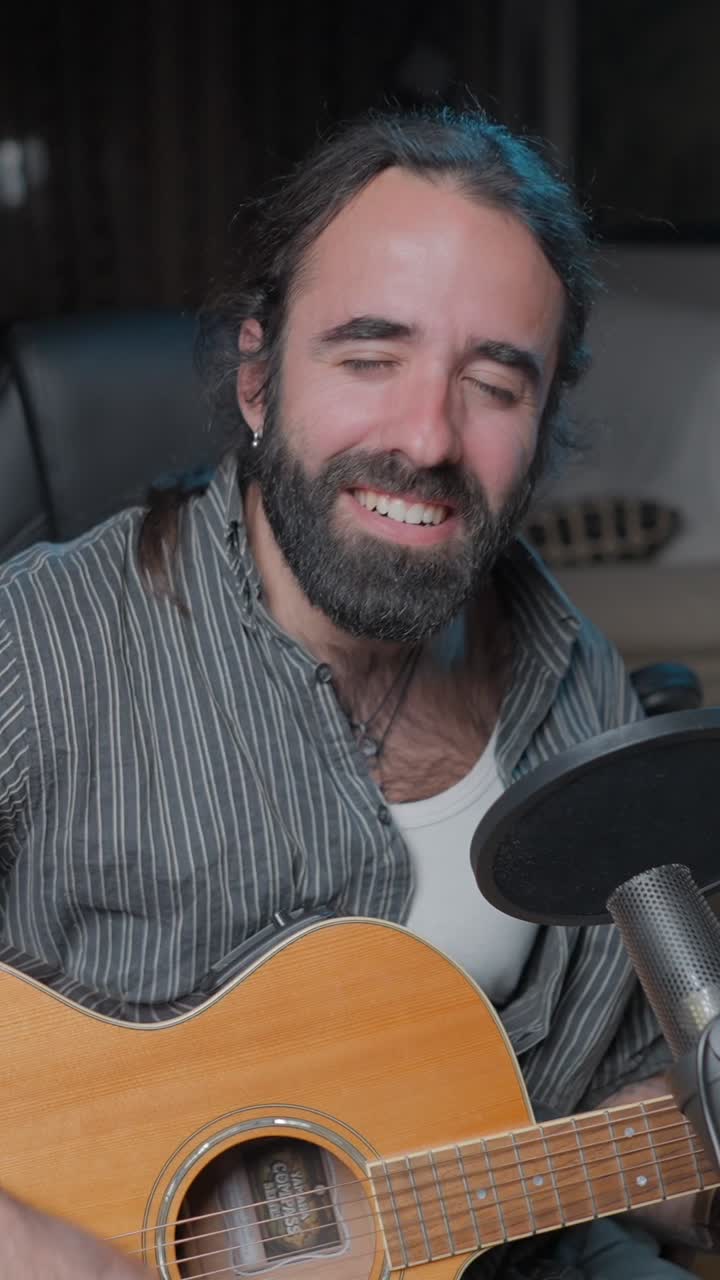 Man playing acoustic guitar and singing with a microphone in a studio