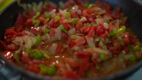 cooking diced tomatoes, onions, and green peppers in a pan