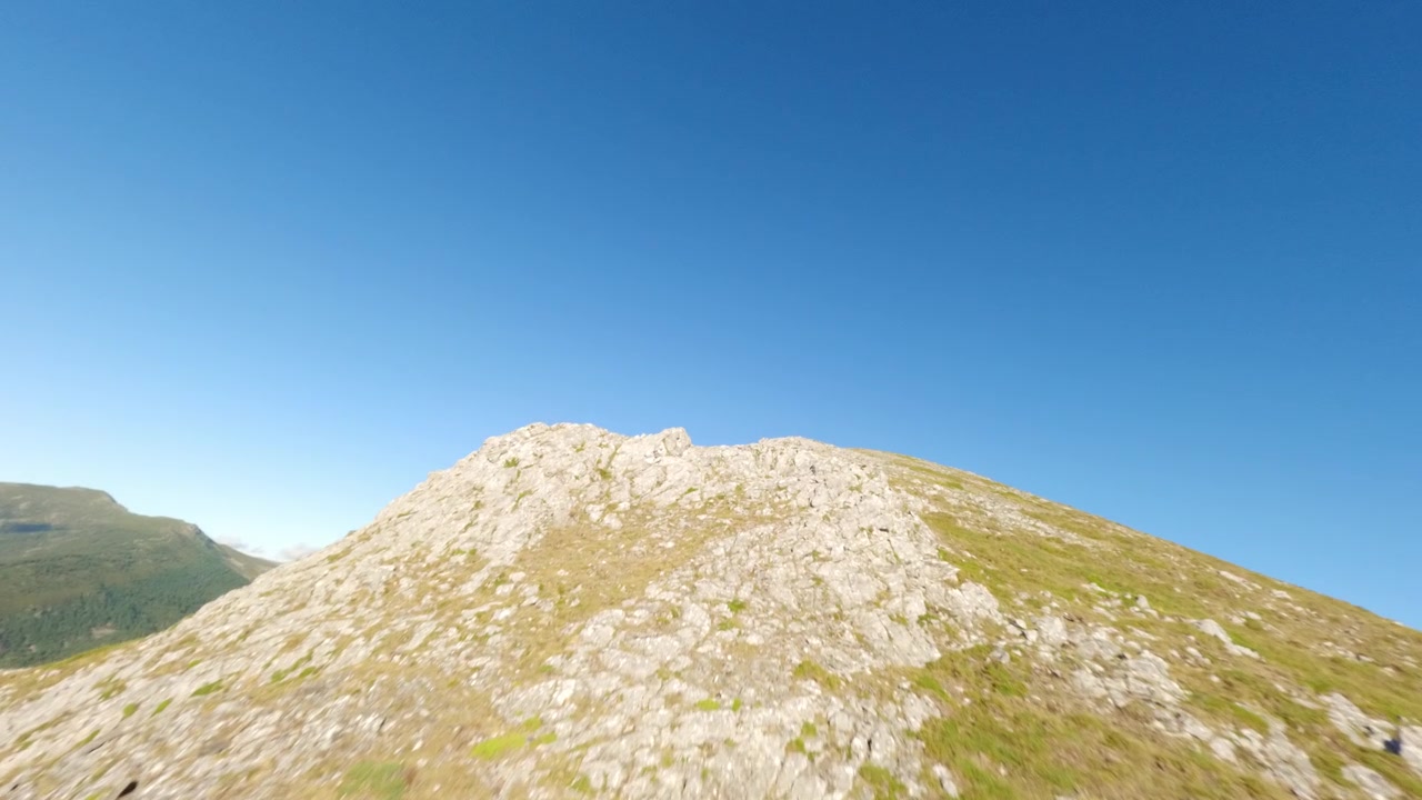Dynaaminen FPV-dronekuva liitämässä jylhän vuorijonon ja kivisen huipun yli kirkkaan sinisen taivaan alla Isobassa, Leonissa. Täydellinen matkailu-, seikkailu- ja luontodokumentteihin.