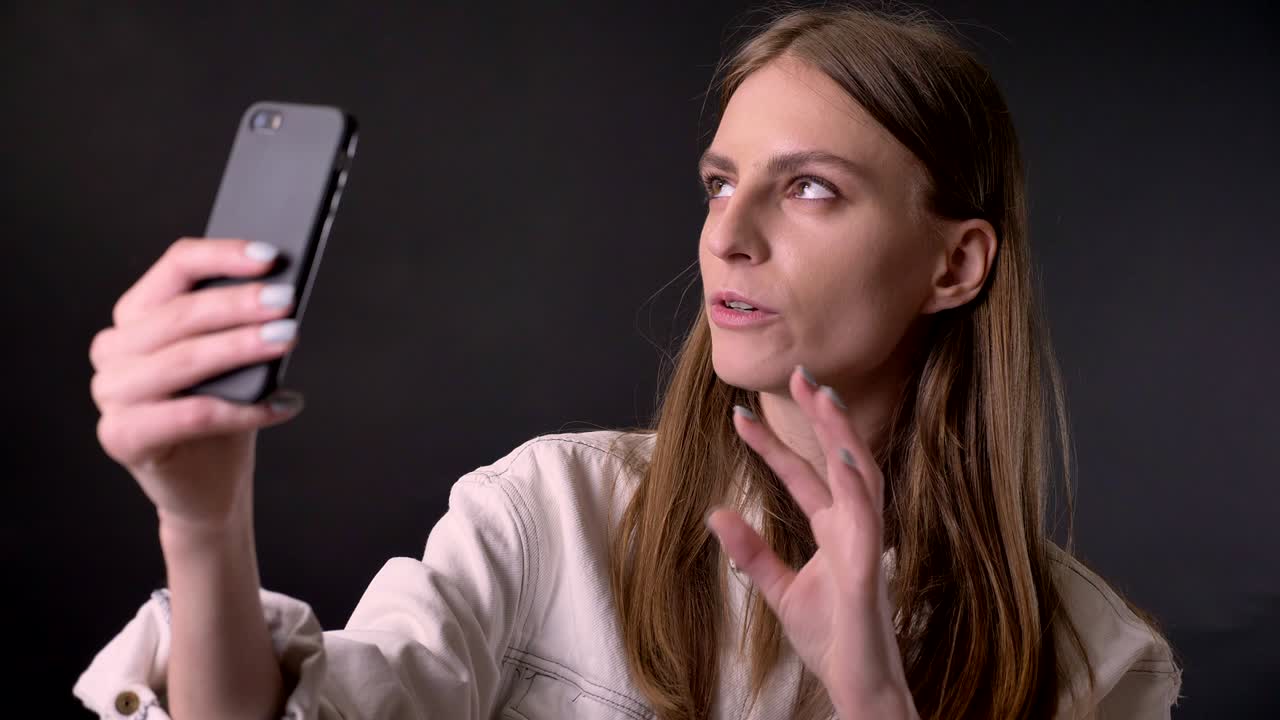 chica fresca se agita en el videochat en el teléfono inteligente, concepto de comunicación, fondo gris