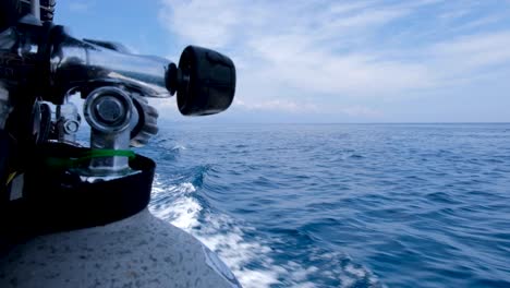 closeup of a scuba diving oxygen tank ready for dive action in a moving motorboat with wake and waves in stunning blue sea