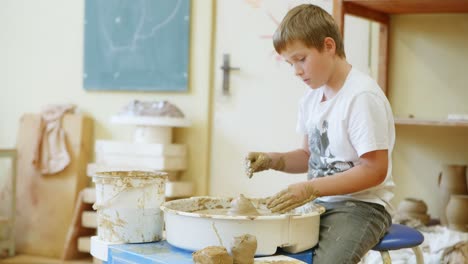 a boy in a pottery workshop, working on a potter's wheel