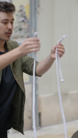 man demonstrates or explains something while holding a white rope