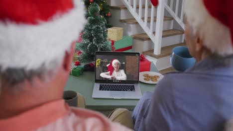 Happy-senior-caucasian-couple-on-video-call-on-laptop-with-granddaughter-at-christmas-time