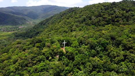 orbit shot of white cross deep in green mountain landscape, ermita hill, baler, philippines