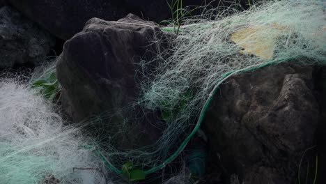 cerca de la red de pesca comercial abandonada como basura en las rocas del lado del océano
