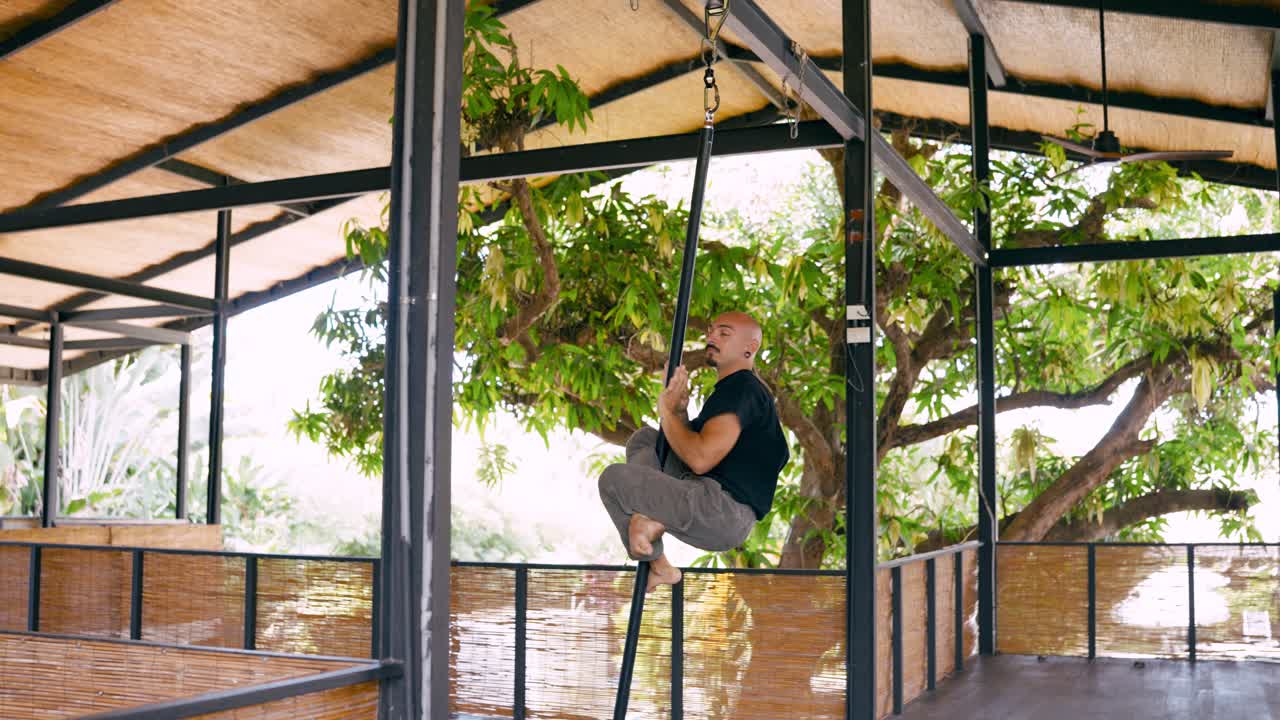 Uomo che pratica danza aerea al palo in uno studio all'aperto