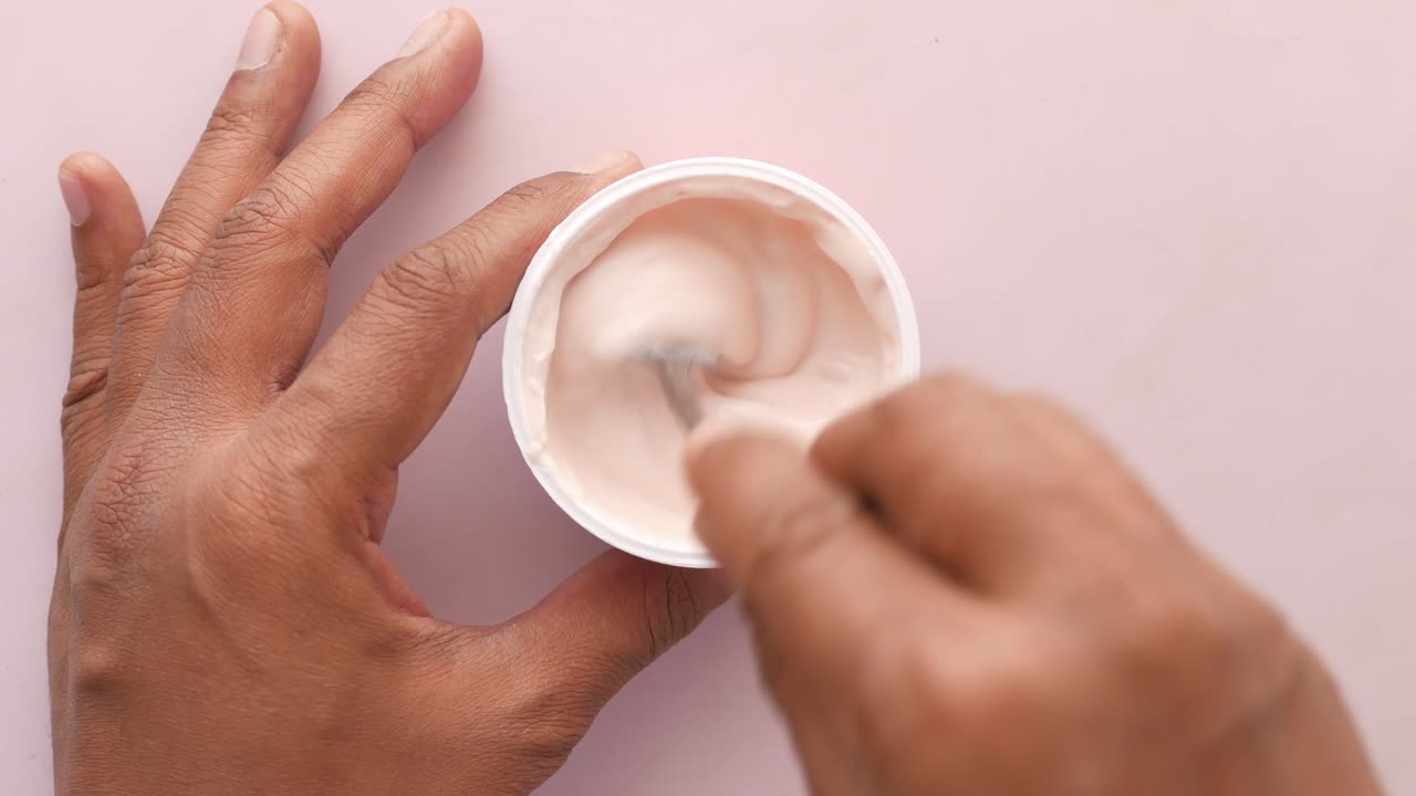 свежий йогурт в пластиковом контейнере и ложка на столе