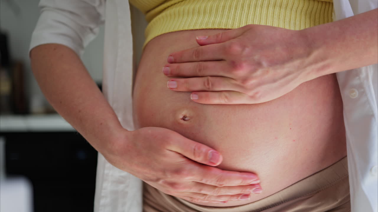 Primo piano di una donna che si massaggia la pancia con l'olio durante la gravidanza
