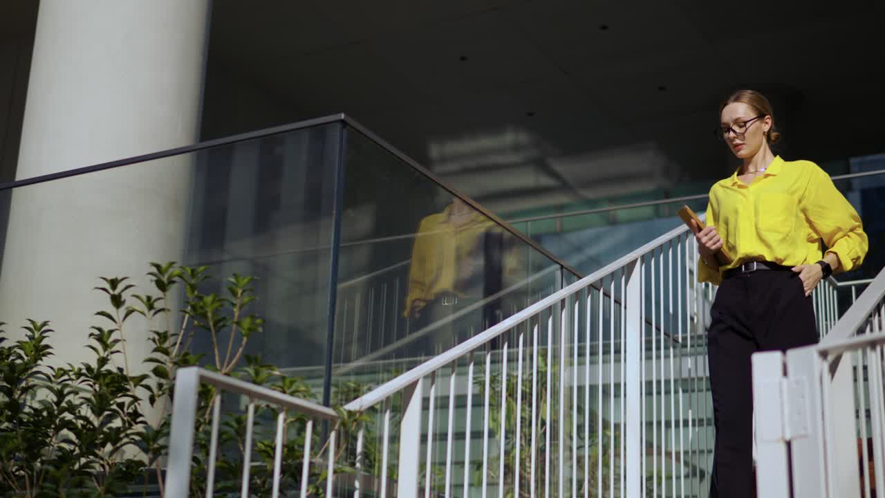 Empresária elegante com camisa amarela e óculos caminhando