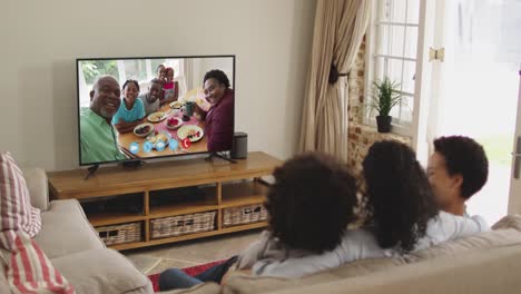 아프리카계 미국인 가족 이 집 에서 소파 에 앉아 tv 에서 비디오 통화 를 하고 있다