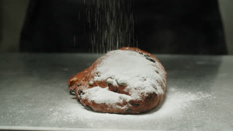 sprinkling powdered sugar on a stollen