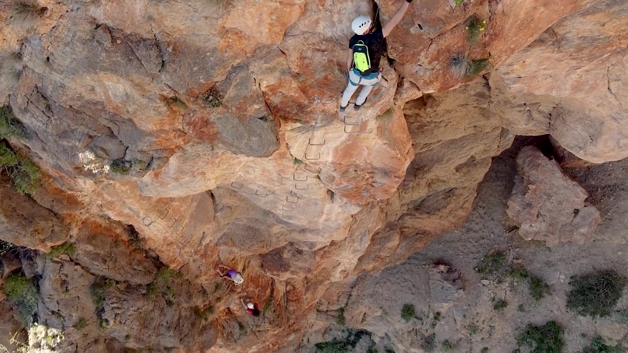 Via ferrata ascension by group of friends . Aerial drone view of mountain and mountaineers climbing in Alicante, Spain.
