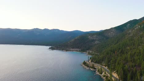 coches conduciendo por una hermosa carretera junto al lago con montañas y agua azul del lago tahoe en la sierra nevada en un día nublado
