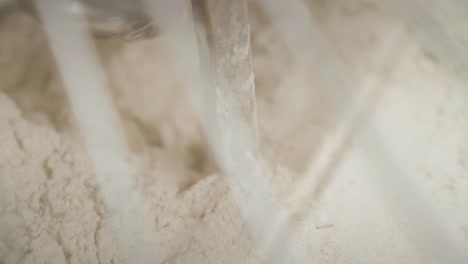 closeup of electric mixer mixing in flour into the dough