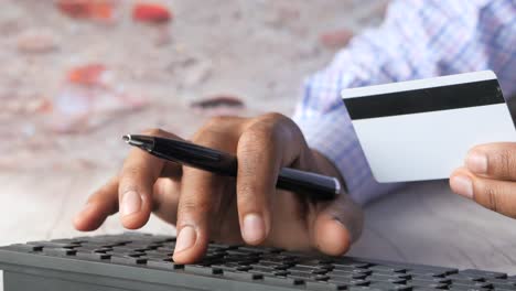 person holding credit card and pen over a keyboard