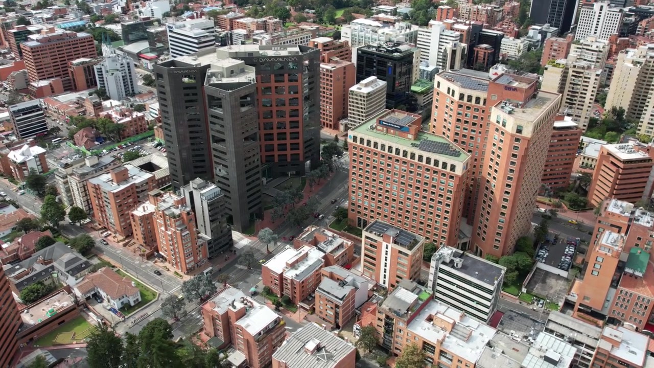 Um complexo entroncamento rodoviário com tráfego intenso e montanhas ao fundo. Vista aérea de drone mostrando um hyperlapse do tráfego da cidade de Bogotá.
