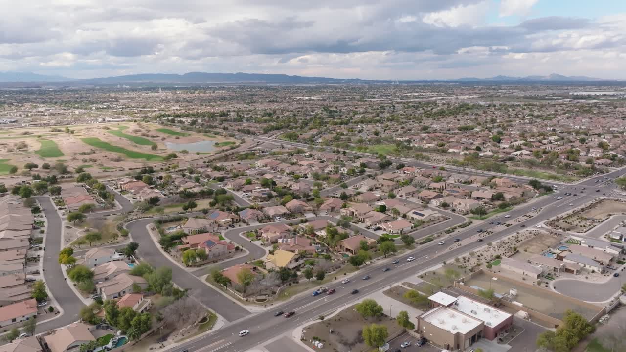 tomada aérea de una carretera de tráfico concurrido en arizona con una cancha de golf en la distancia. tomada amplia. área de vivienda con casas en el suburbio de chandler town.