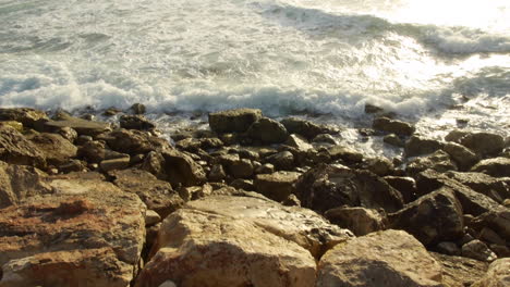 Wellen,-Die-Auf-Den-Felsen-Am-Ufer-Zusammenbrechen,-Helle-Abendsonne