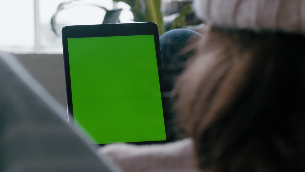 woman using digital tablet computer watching green screen relaxing at home on couch enjoying online entertainment