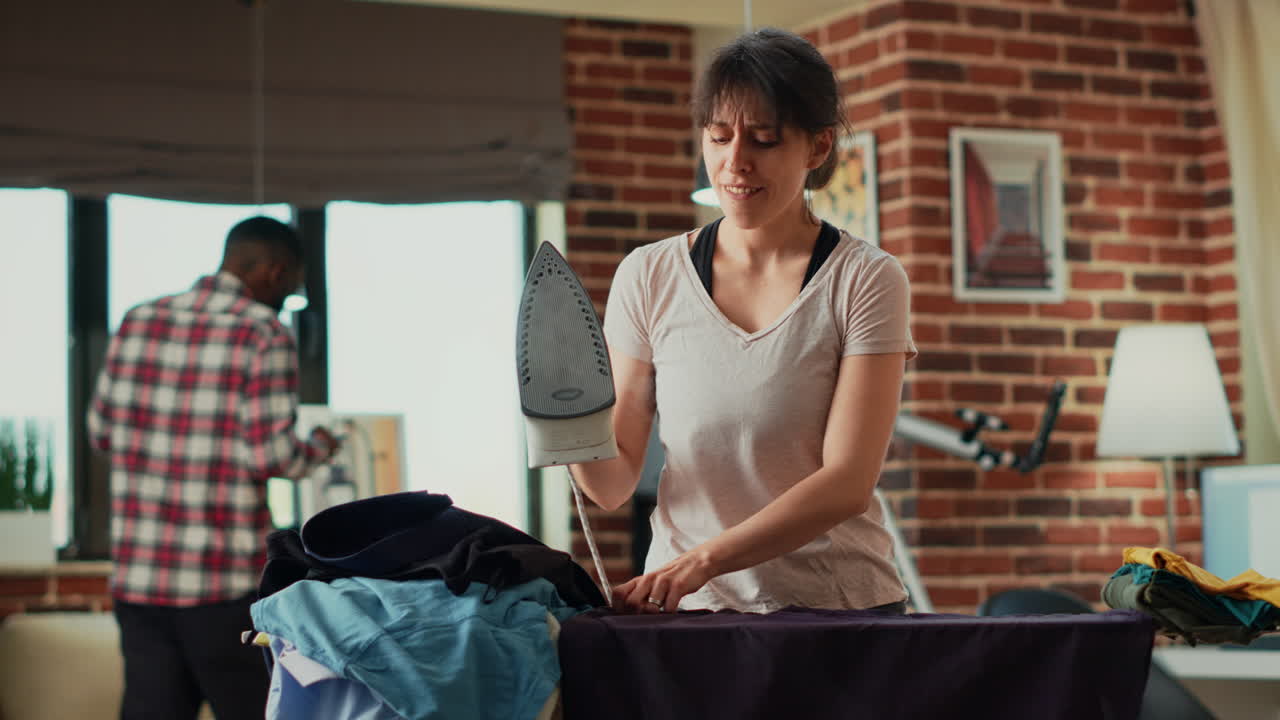 Happy adult singing and dancing while she irons clothes