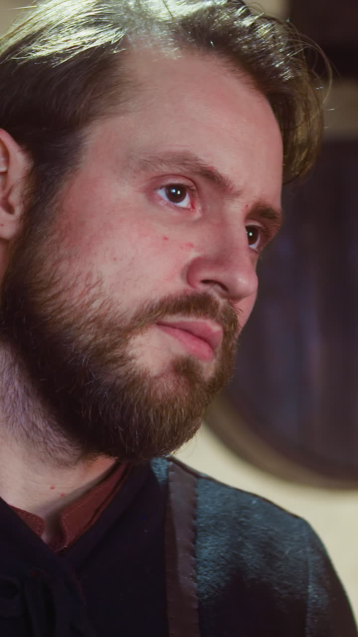 el hombre preocupado está de acuerdo con su amigo en la taberna medieval. el valiente hombre barbudo se une a una peligrosa búsqueda asintiendo con la cabeza en la posada.