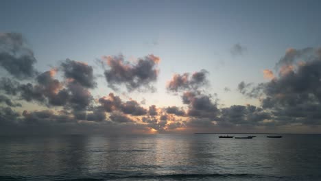 Pequeños-Barcos-De-Pesca-Anclados-Cerca-De-La-Costa-De-La-Playa-De-Uroa-En-La-Isla-De-Zanzíbar-Durante-La-Puesta-De-Sol,-Tanzania-áfrica,-Muñeca-Aérea-En-Tiro