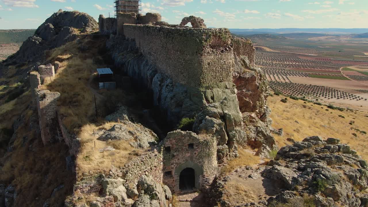 Drone in volo ascendente all'ingresso del Castello di Peña Negra a Mora, Toledo, che mostra la sua forma unica sulla cima della collina, il mastio in restauro e ampi uliveti sullo sfondo
