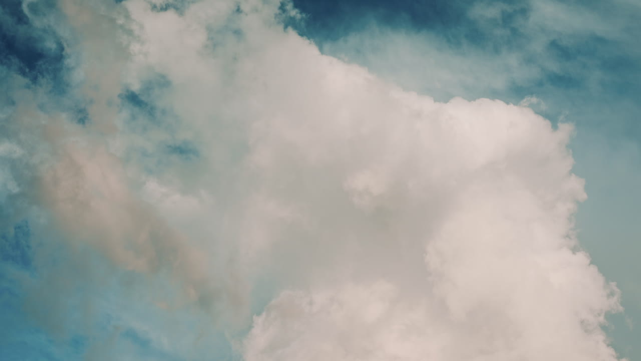 Close up of large, soft white clouds drifting across a blue sky