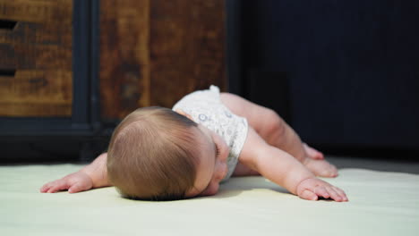 baby boy smiling on the ground while on his stomach learning how to crawl