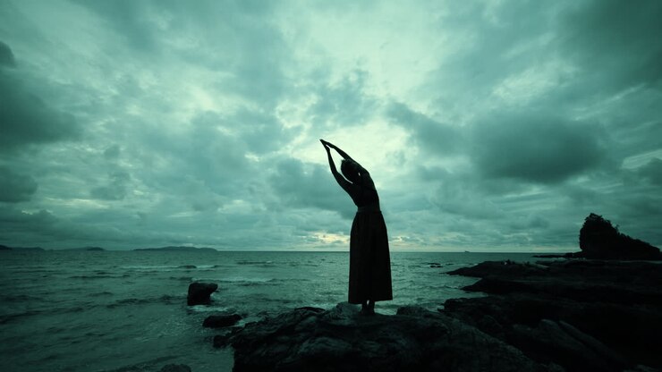 Donna in posa yoga su una spiaggia con un tramonto spettacolare