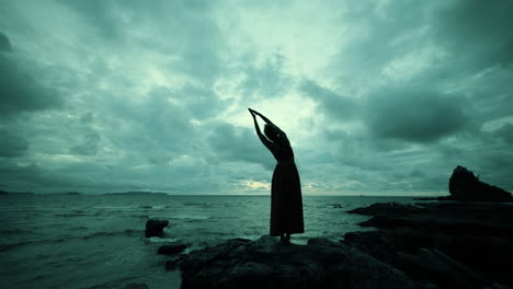 Woman in yoga pose on a dramatic sunset beach