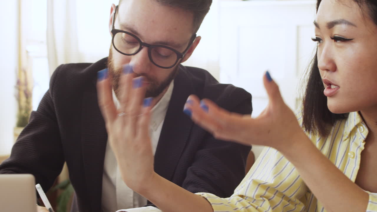 팀 회의 중에 노트북 컴퓨터를 보면서 테이블에 앉아 토론하는 세 명의 다민족 동료 그룹