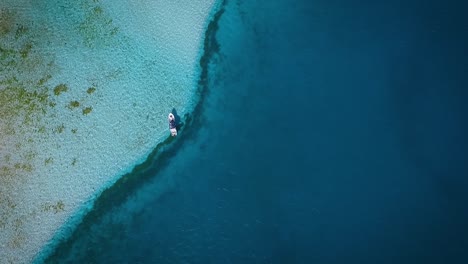 Vista-Aérea-De-Un-Pequeño-Barco-De-Pesca,-Flotando-En-El-Mar-Caribe-Azul,-En-Los-Roques-Venezuela