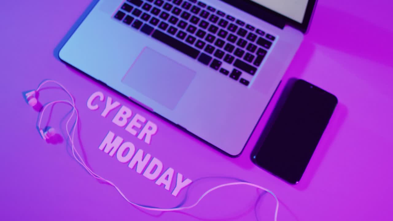 composición de portátil, auriculares y teléfono inteligente con texto de cyber monday en fondo púrpura