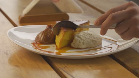 hand using spoon to cut delicious flan with dulce de leche and cream