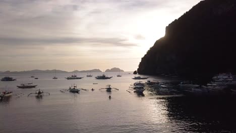 4K-Aerial-Drone-Shot-of-Fishing-and-Tour-Boats-in-the-Bay-at-Corong-Corong-Beach-in-El-Nido,-Palawan,-Philippines