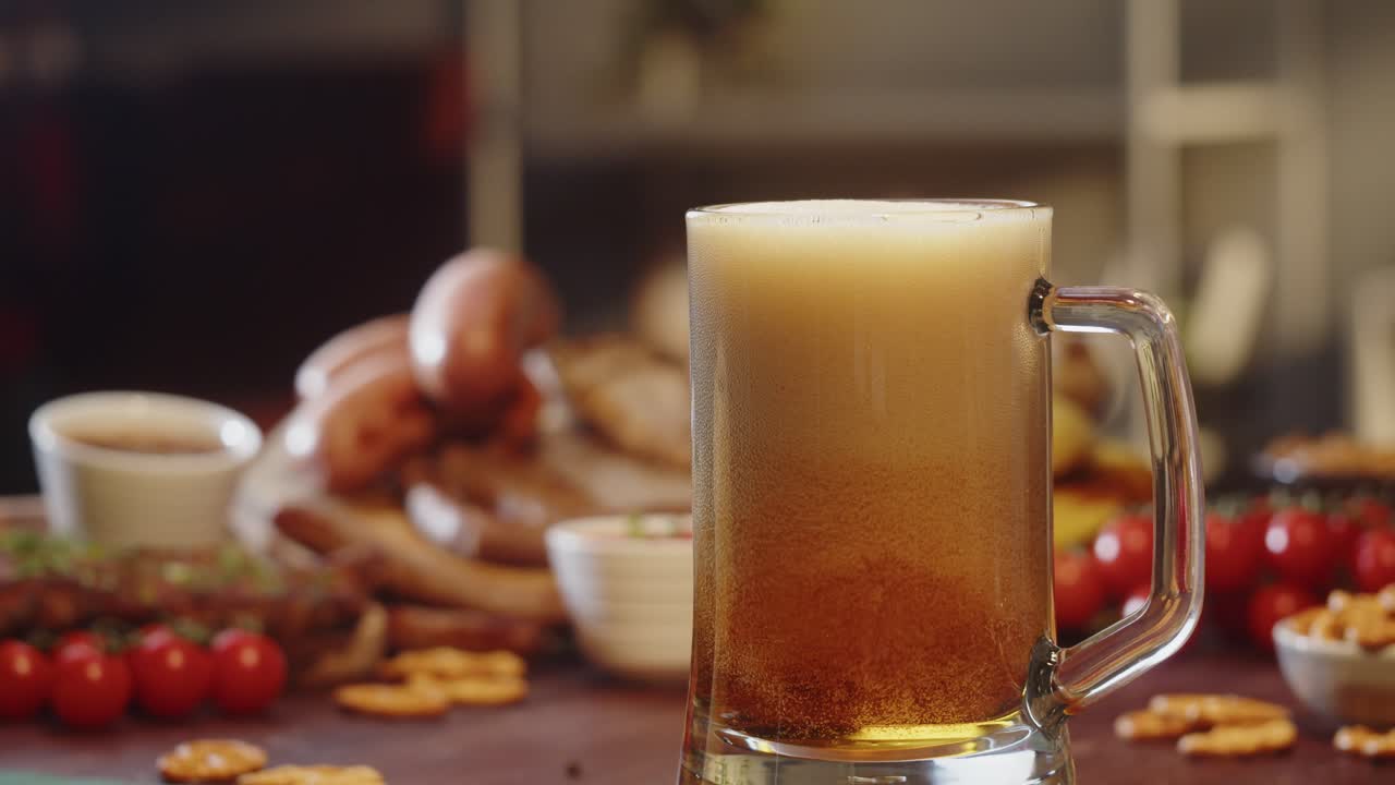 Birra dorata versata in un boccale di vetro con snack sullo sfondo