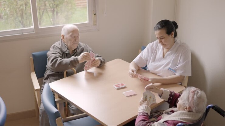Senior people and caregiver playing cards in a nursing home